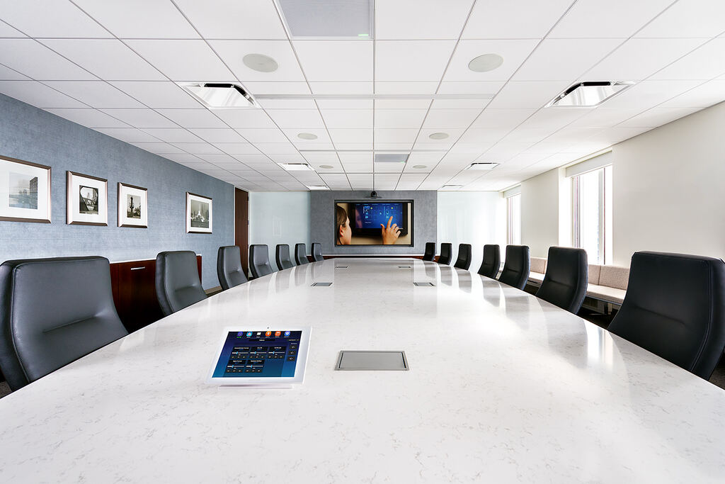 Meeting room with a long conference table, tabletop control, and wall display